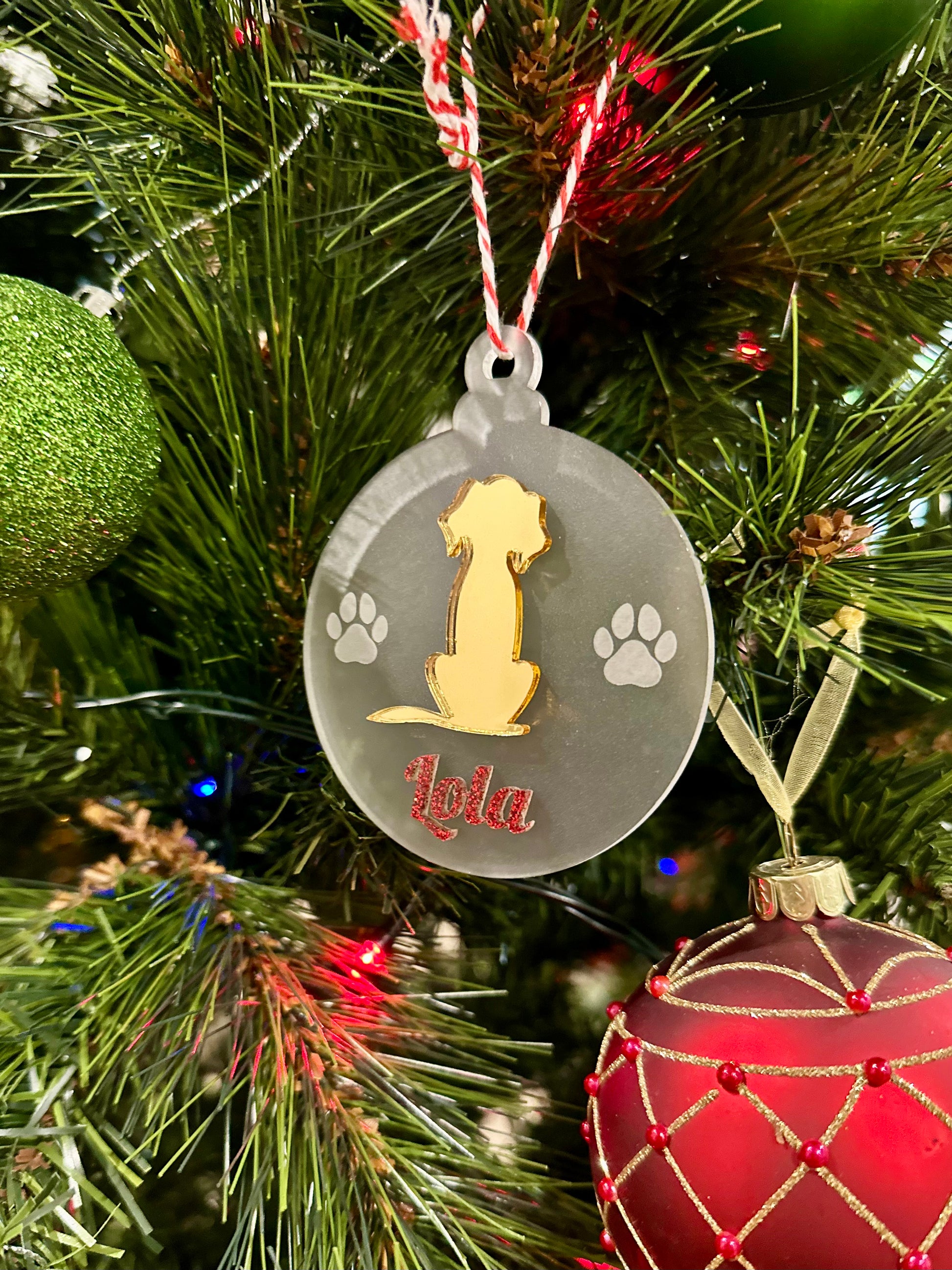 Decorative Christmas ornament with a dog design and 'Lola' engraved, hanging on a tree.